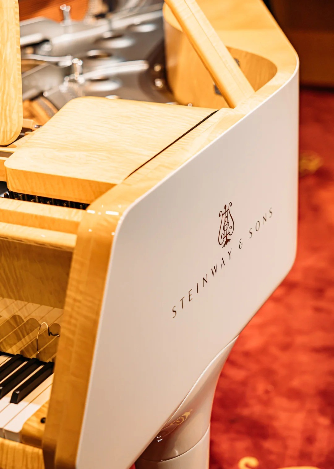 Czerwona etykieta Steinway & Sons z logo na drewnianej części fortepianu salonowego