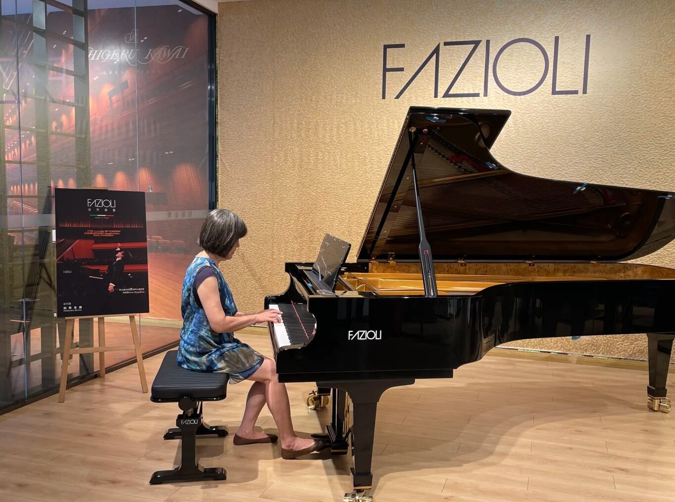 Pianistka w sukni koncertowej grająca na czarnym fortepianie Fazioli na scenie