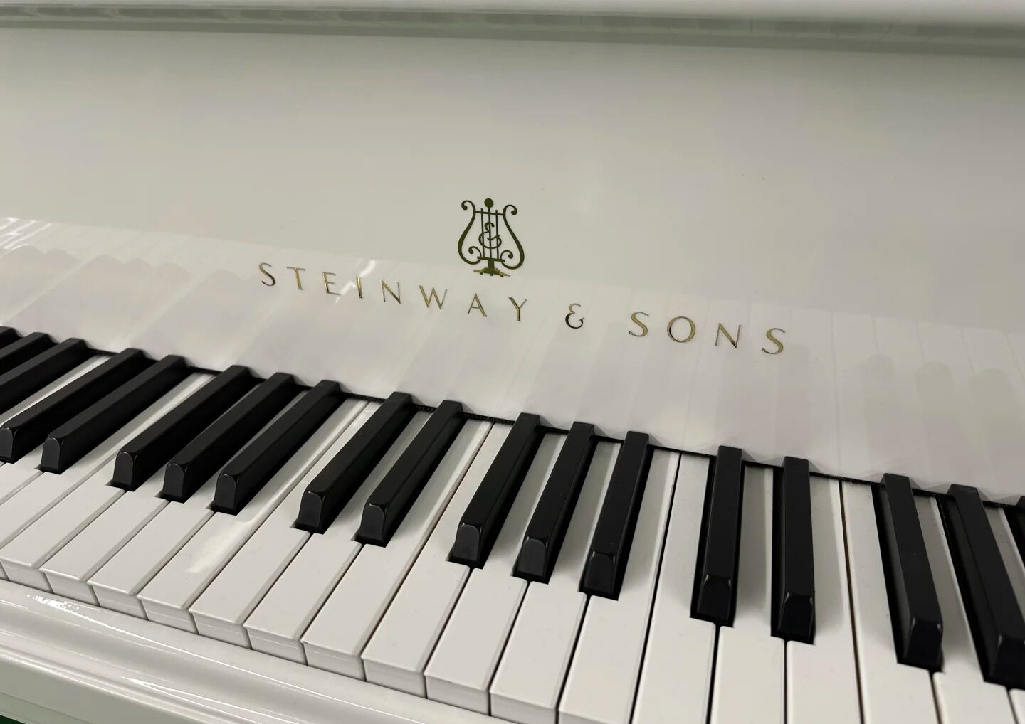Klawiatura fortepianu Steinway & Sons z widocznym złotym logo lira nad klawiszami