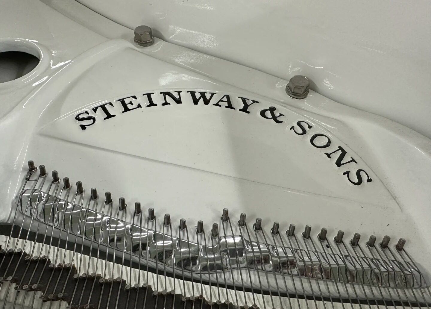 Złota plakietka Steinway & Sons na ramie żeliwnej fortepianu z widocznymi feltrami