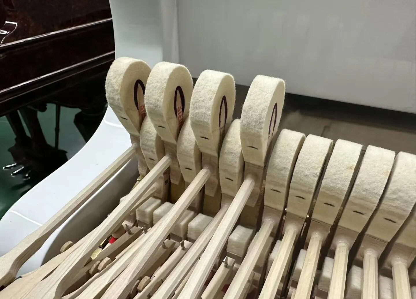 Białe felty fortepianowe na taśmie podczas montażu w fortepianie - prace warsztatowe