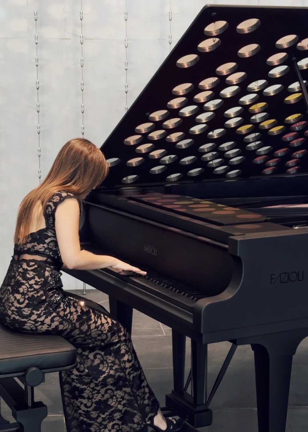 Pianistka w sukni w groszki grająca koncertowo na fortepianie Fazioli z logo marki