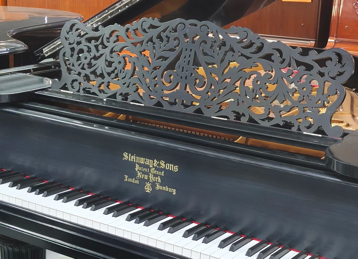 Czarny fortepian Steinway & Sons z charakterystyczną złotą rosetą i ozdobnym pulpitem