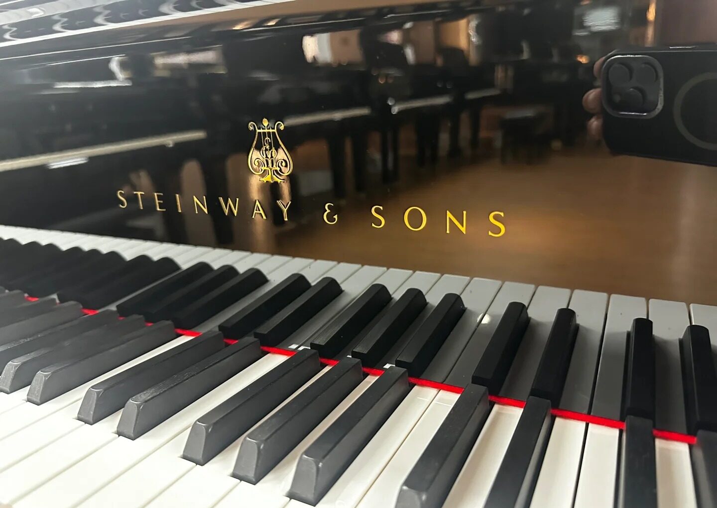 Czarny fortepian Steinway & Sons z widocznym logiem marki i charakterystyczną ozdobną krzywą boczną