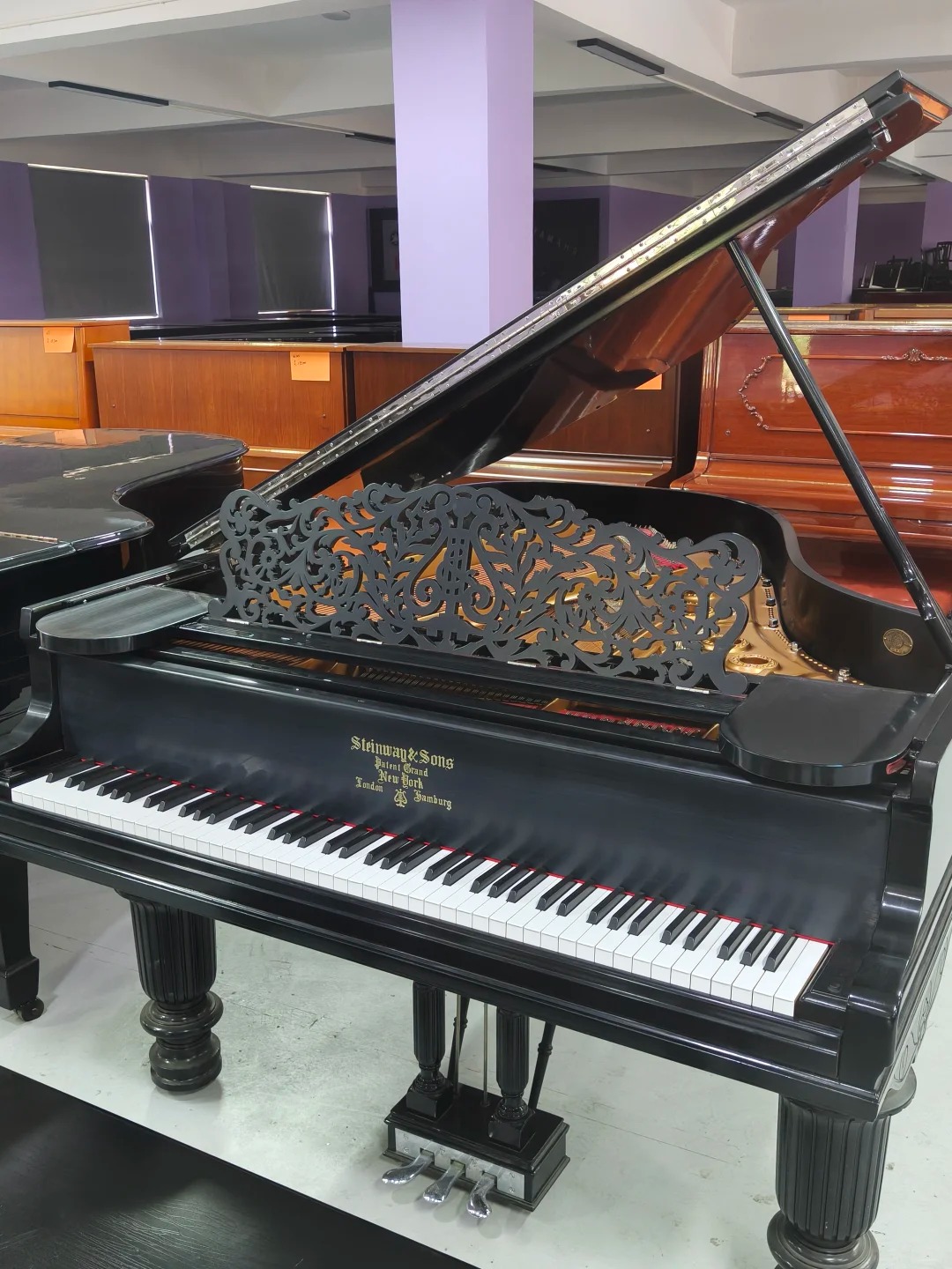 Piano à queue Steinway & Sons O-180 avec couvercle ouvert et touches blanches et noires.
