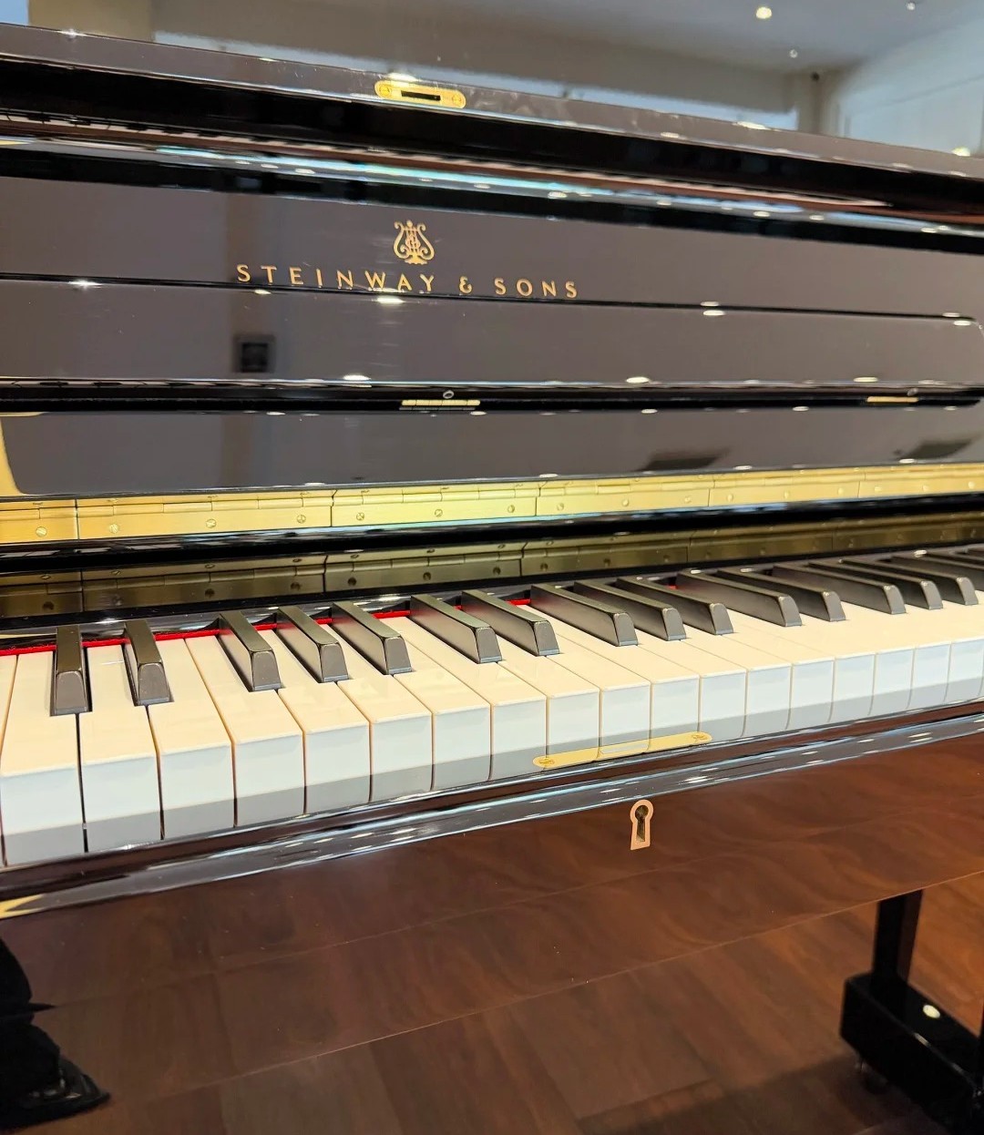 Piano droit Steinway K-132 – vue de showroom avec tapis logo