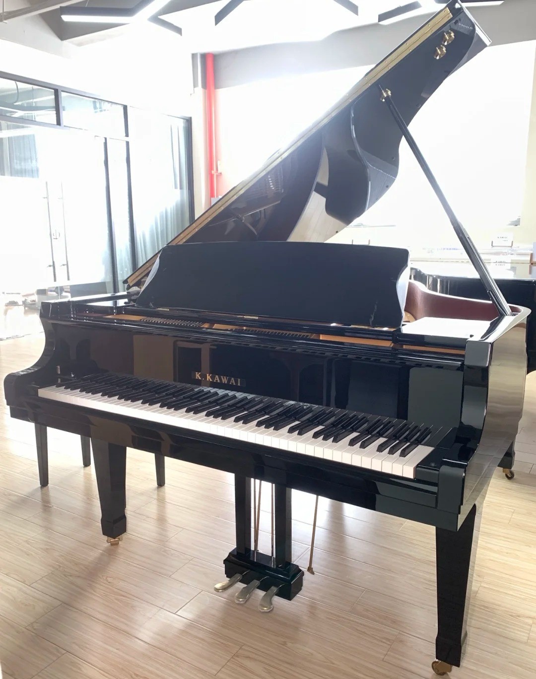 Piano à queue Kawai GX-2 finition polyester noir poli vu de trois quarts face en showroom, couvercle ouvert et clavier 88 touches